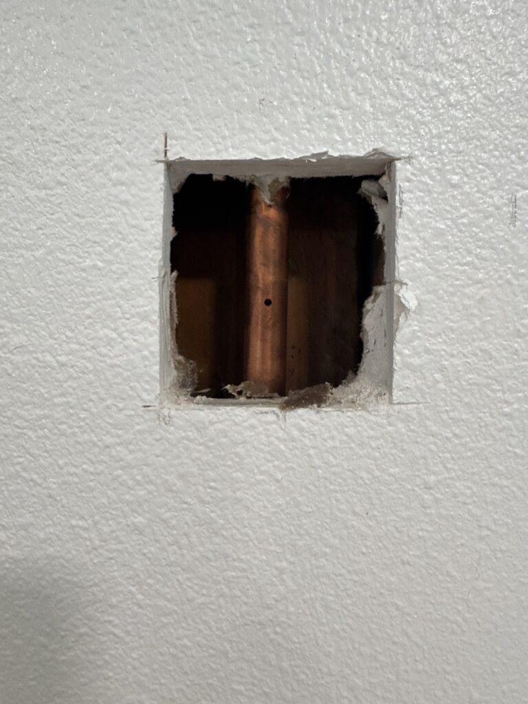 Access opening exposing concealed copper water piping