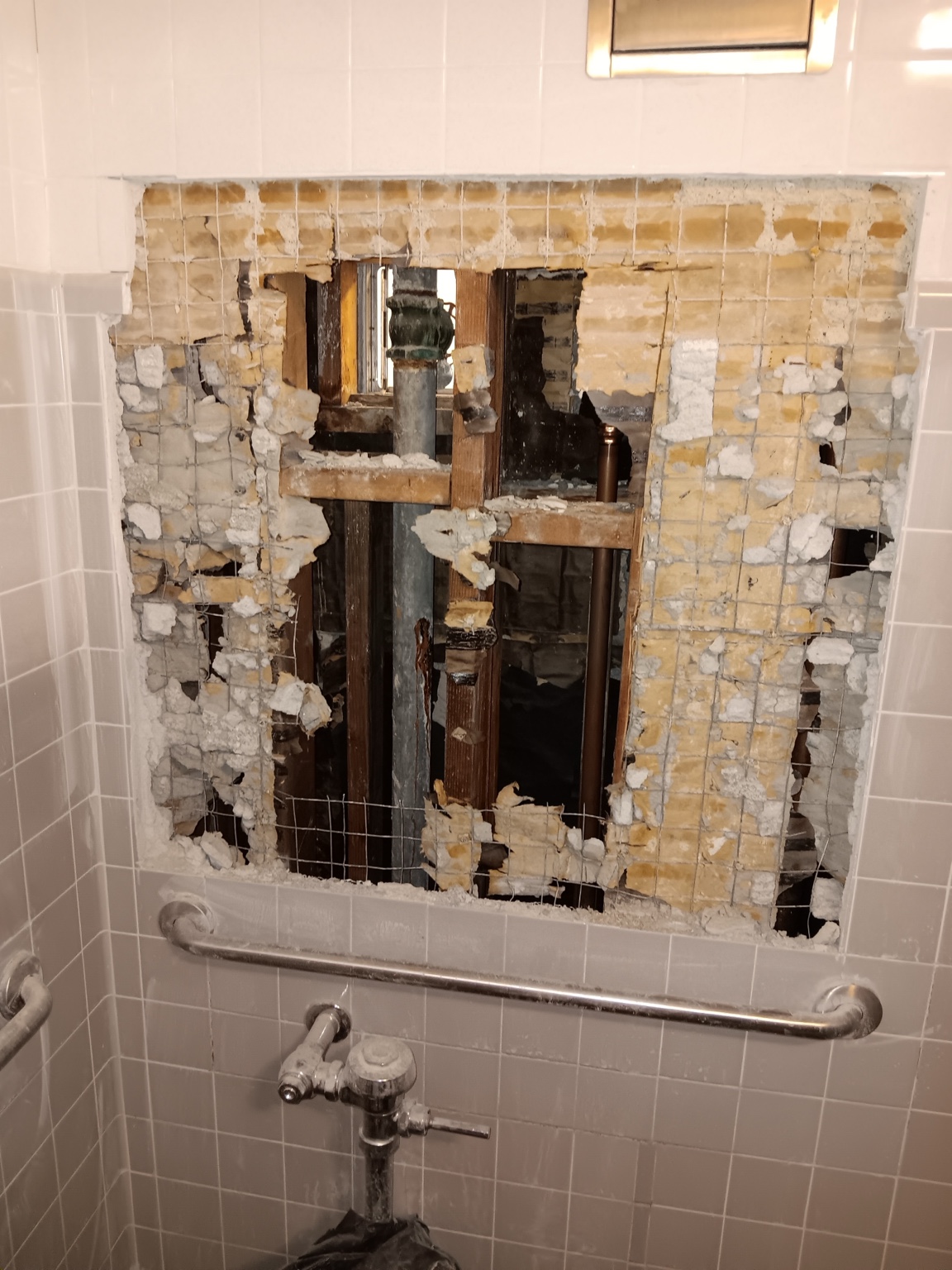 Before repair: original galvanized water supply pipe exposed behind a restroom wall at a Simi Valley business